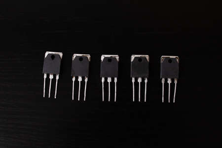 Black transistors on a black wooden table close up