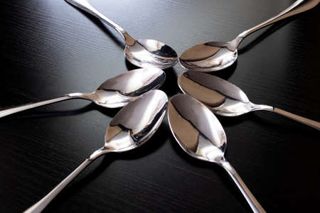 Many spoons on a black wooden table close up