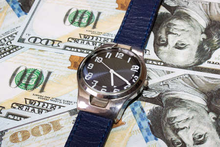 Blue wrist watch on dollars close up, the price of timeの写真素材