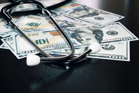 Stethoscope on hundred dollar bills close up, cost of medicineの写真素材