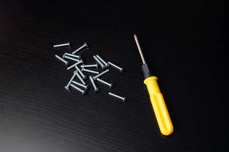 Screwdriver and screws on a wooden table close upの写真素材