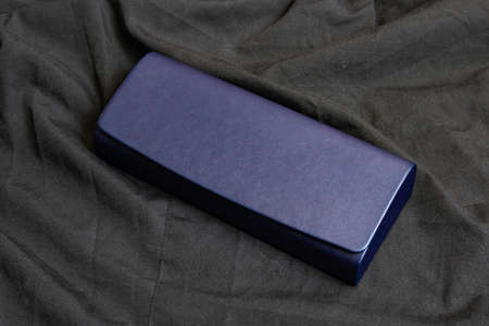 Blue case for sunglasses on black textile close up