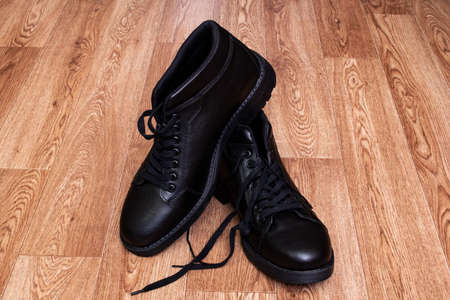 Black leather mens boots on wooden floor close up