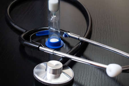 Stethoscope and hourglass on a wooden table