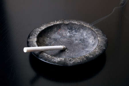 A lit cigarette and an ashtray close upの写真素材
