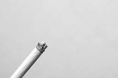 A lit cigarette on gray background close upの写真素材