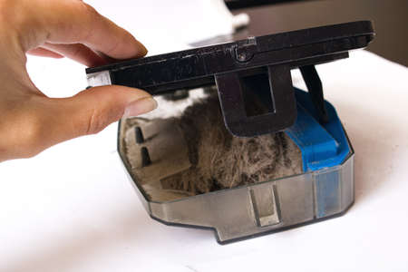 Vacuum cleaner container and hand on a white backgroundの写真素材