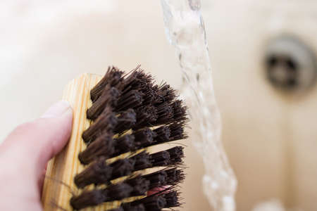Shoe brush in hand and water jet close upの写真素材