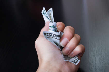 Hand holds rumpled dollars on a wooden backgroundの写真素材