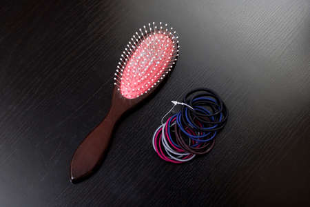 Pile of hair ties and hairbrush on a wooden tableの写真素材
