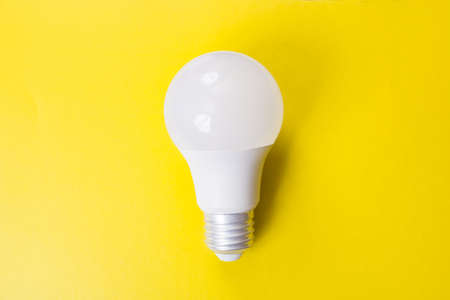 Light bulb on bright yellow background close up