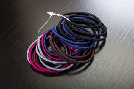 Pile of hair ties on wooden background close up
