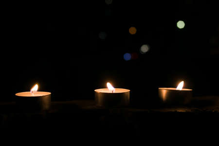 Three small candles in the dark close upの写真素材