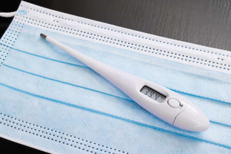 Thermometer and medical mask on a blue background