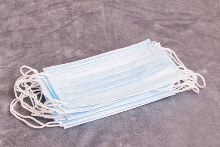 Heap of medical masks on a gray background