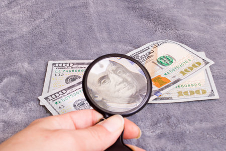 Checking a dollar bill for authenticity with a magnifying glassの写真素材
