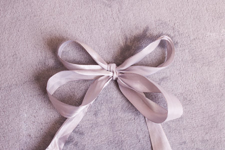 Bow made of gray ribbon on gray background close upの写真素材