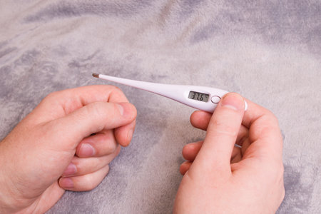 Thermometer with elevated temperature in hand close up