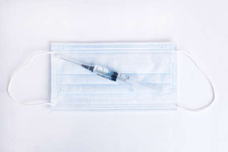 Syringe and medical mask on a white background