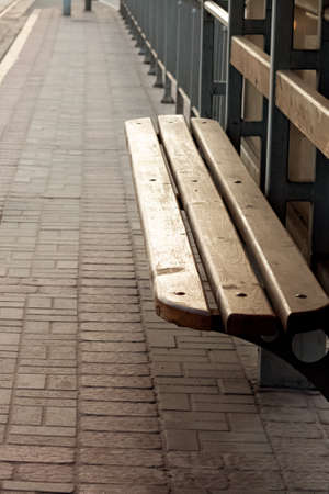 Wooden bench at ramway station in sunloght close up