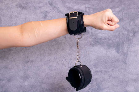 Hand with scars and handcuffs on a gray backgroundの写真素材