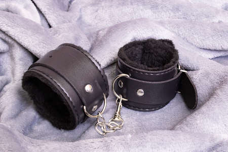 Black leather handcuffs on a gray background close up