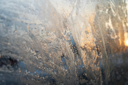 Frosty patterns on glass against the background of the morning sun