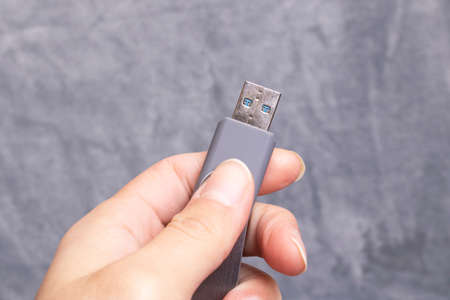 USB flash drive in hand on a gray backgroundの写真素材