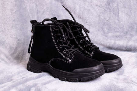 Pair of womens black boots on a gray background