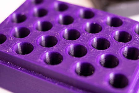 Many holes in purple plastic close up, concept of trypophobia