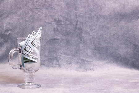 Dollars in a mug on a gray background, copy space