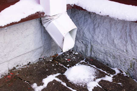 Metal downpipe in ice and snow close upの写真素材