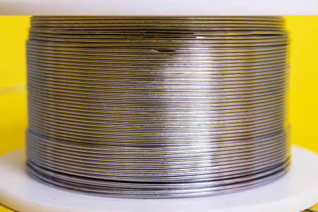 Metal wire spool on a yellow background close upの写真素材