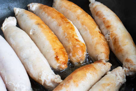 Meat sausages are fried in a pan close upの写真素材