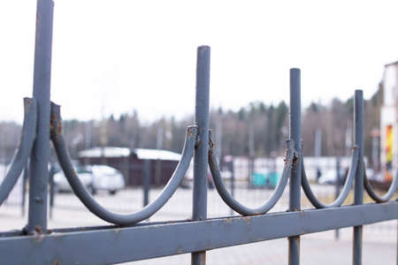 Old metal forged fence on the background of the roadの写真素材