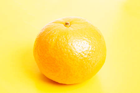 Yellow tangerine on a yellow background close upの写真素材