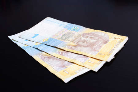 Three banknotes of Ukrainian hryvnia on a black background close up