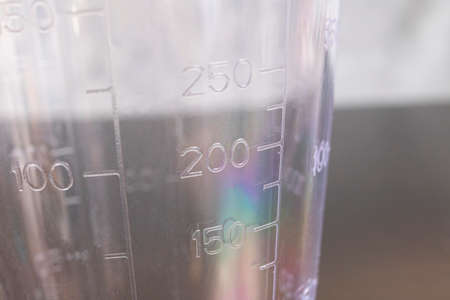 Plastic measuring cup on a gray background close upの写真素材