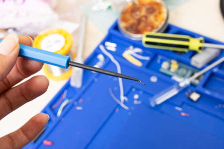 Small soldering tools in hand on desktop background close up