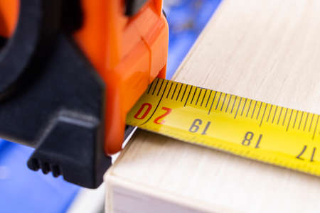 Measuring a wooden board with a construction tapeの写真素材