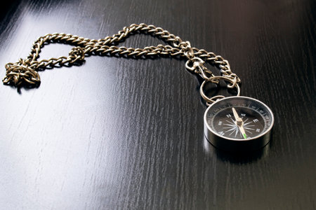 Compass on a chain on a wooden table close up