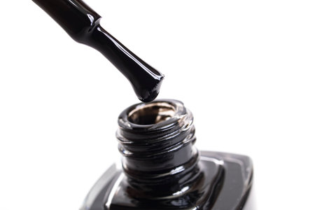 Black nail polish and brush isolated on white background close up