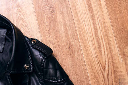 Black leather jacket on a wooden background copy space