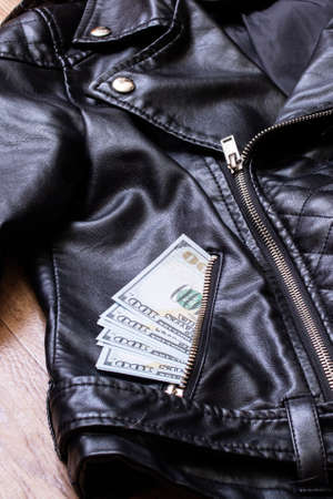 Dollars in the pocket of a leather jacket close up