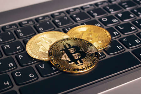 Three bitcoins on a computer keyboard close upの写真素材