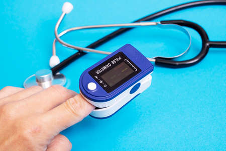 Stethoscope and pulse oximeter on blue background close up