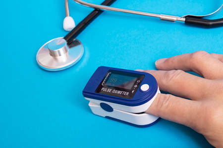 Stethoscope and pulse oximeter on blue background close up