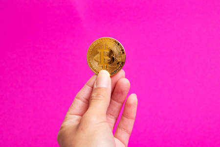 Bitcoins in hand on a pink background close upの写真素材