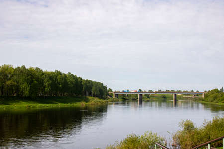 River bank with trees and a bridge for cars in summerの写真素材