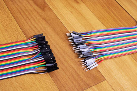 Set of multicolored wires on wooden background close up